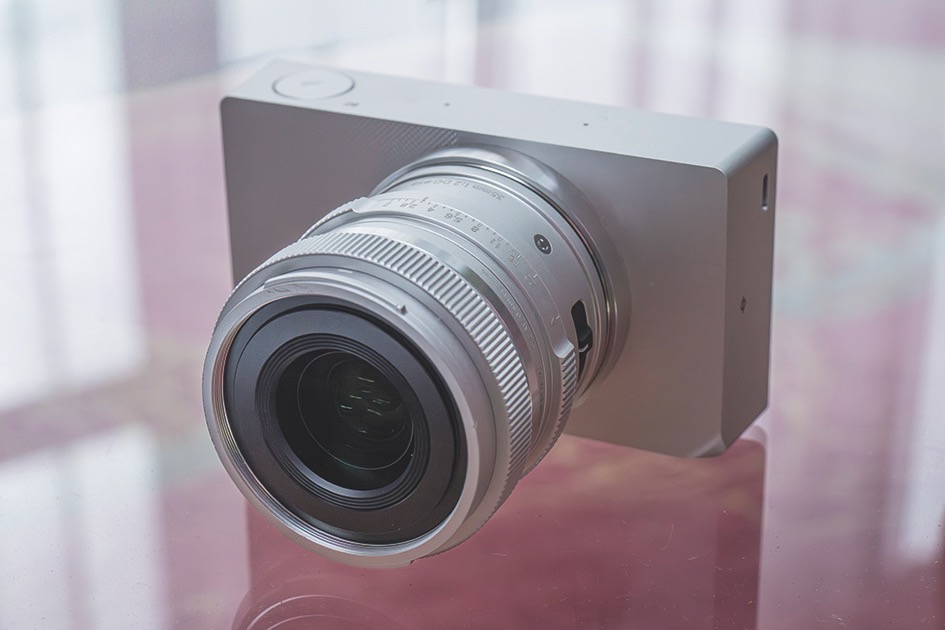 With few buttons, the menu is the only way to navigate. Who cares when the camera looks so cool? A simple silver camera from Sigma with limited controls, sitting on a transparent surface