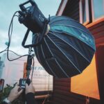 A person operating a large hooded light from Nanlux outside