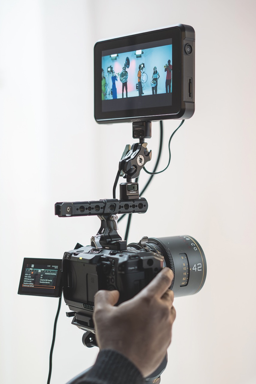 A hand adjusting a Canon camera with a large monitor attached to the top