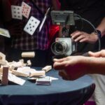 A camera from Pixboom filming cards flying and a wooden block tower falling over on a table