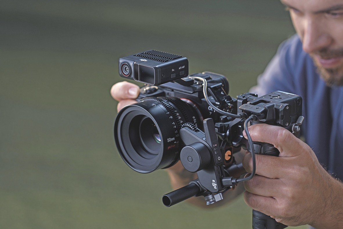 A man holding a camera in a DJI rig, with a blurred grassy background