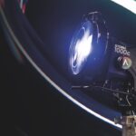 A glowing professional light by Aputure illuminated by a ring light, against a black background