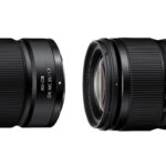Two lenses by Nikon laying horizontally, against a white background