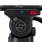 The top of a black tripod by Sachtler with a lever at the back and a red clip, against a white background