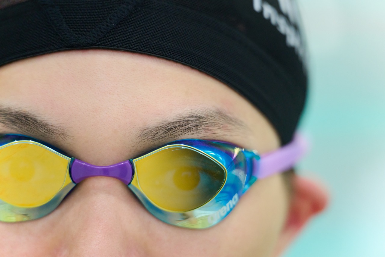 Close up of a person wearing multi-colour goggles and a swimming cap