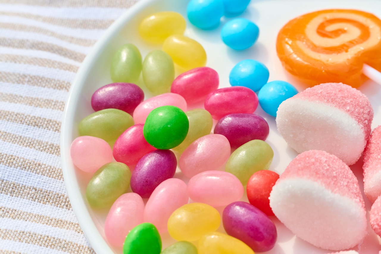 A close up of a plate of colourful sweets sitting on a stripped surface