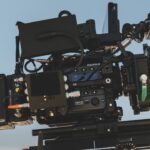 A man wearing a flat cap looking at the monitor of a Fujifilm cinema camera in a desert landscape