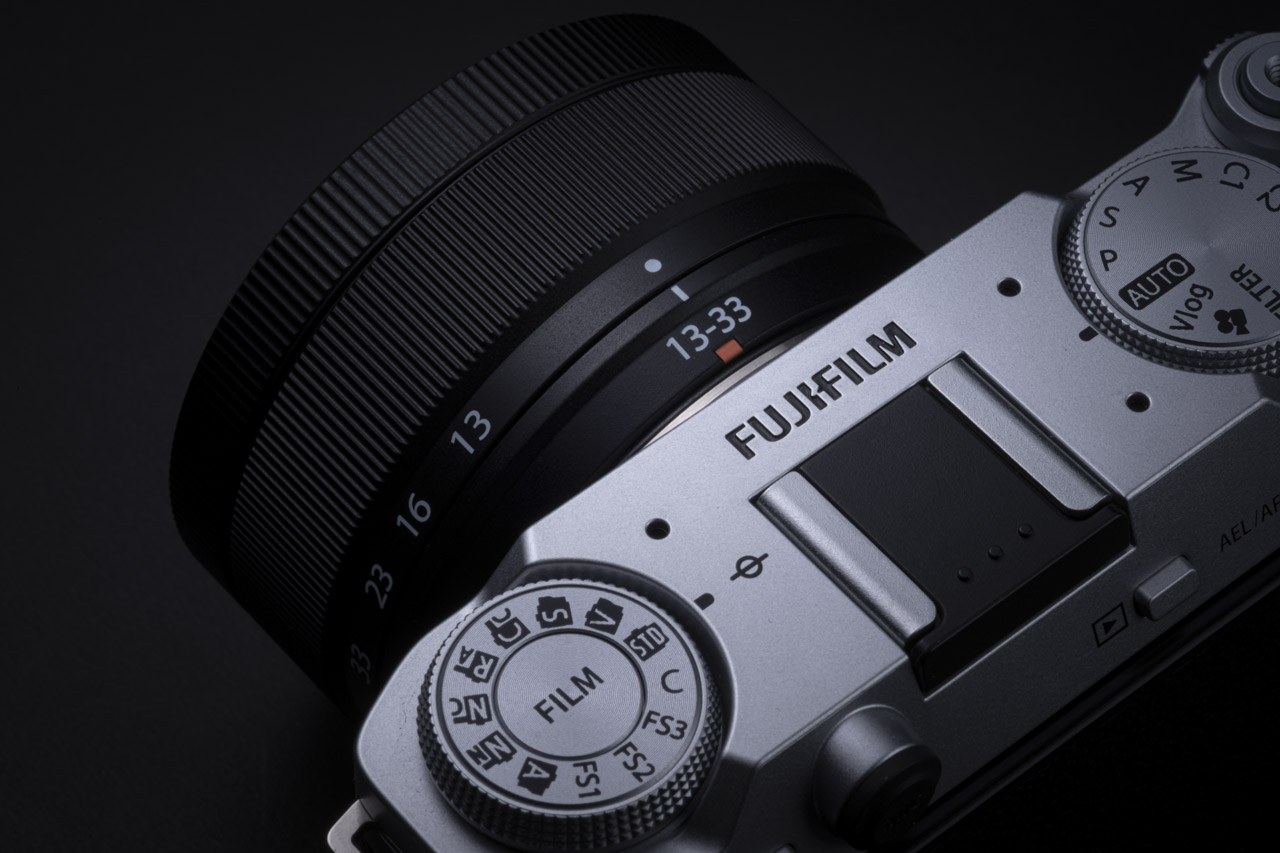 Top view of a Fujifilm camera with a lens attached, against a black background