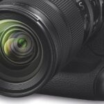 A black Nikon camera with rounded edges, against a white background