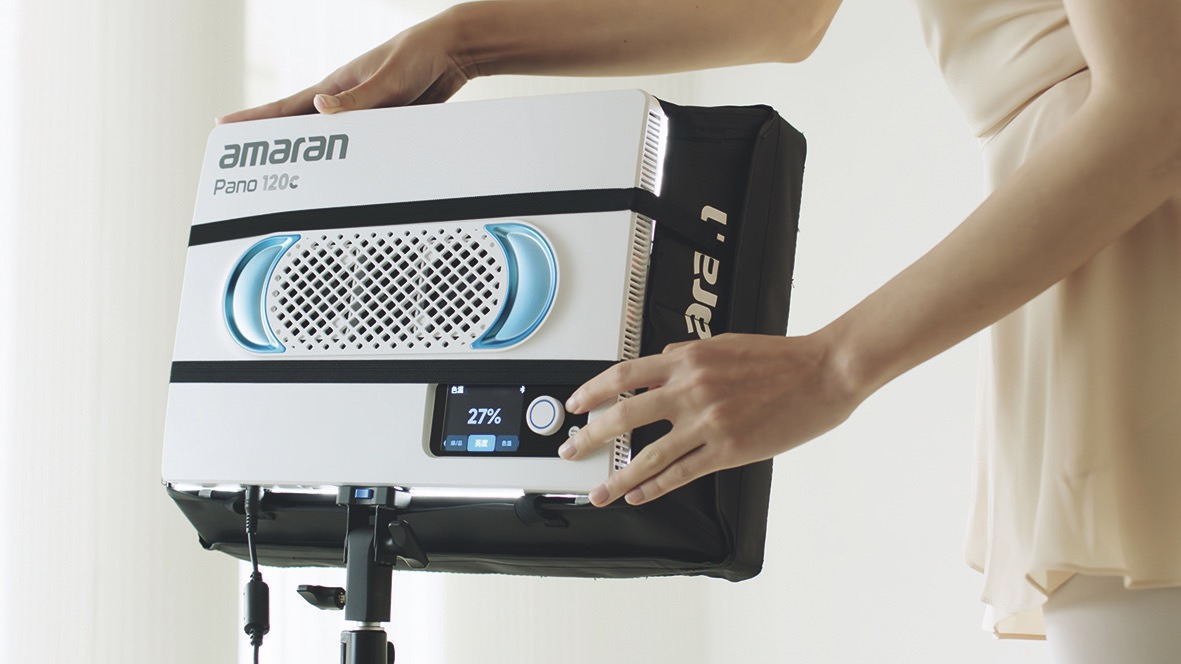 Hands adjusting an Amaran light panel with a blue and white back