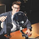 A man sitting at a desk and smiling with a round light from Nanlite