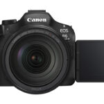 A black camera from Canon with a screen open to the side, against a white background