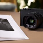 A Leica camera placed on a table next to an open photo book