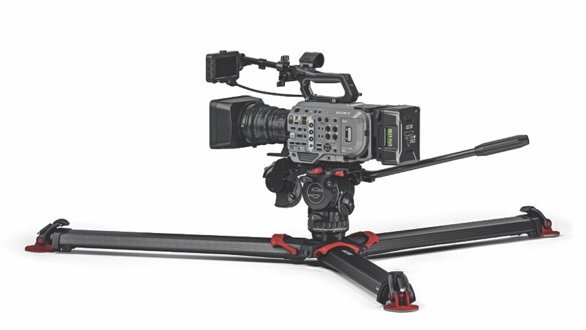 A professional camera placed to a tripod spread flat, against a white background