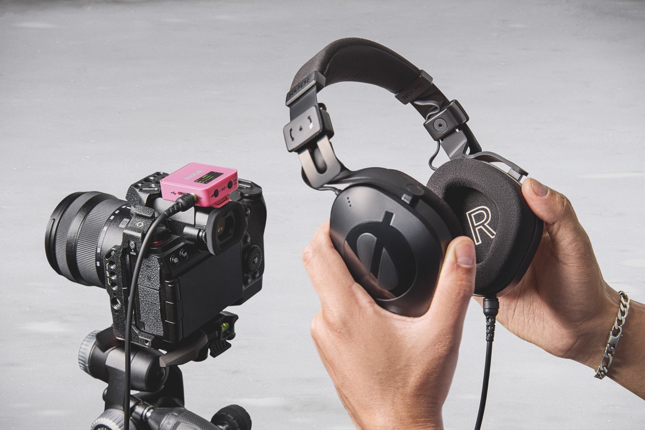 A pair of hand stretching headphones attached to a camera with a pink device attached to the top