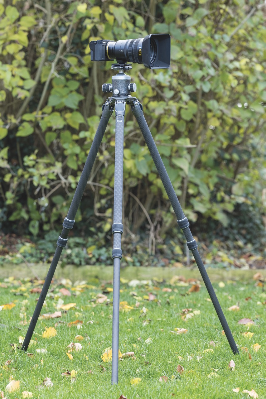 A tripod from Gitzo placed on the grass outside