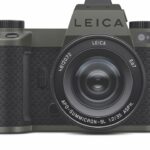 A black camera with textured grip by Leica, against a white background