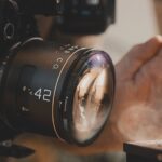 A filter over a lens with a hand blocking light to show smoke wafting in front of the camera