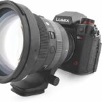 A large, round lens from Sigma attached to a small camera, against a white background