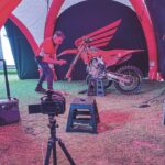 A man fixing a motorbike in a tent with cameras set up