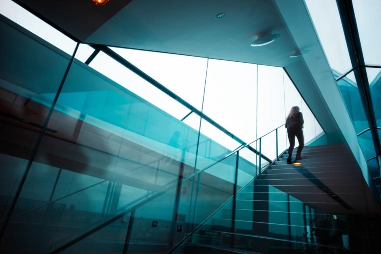 A figure walking up the stairs in a blue office building