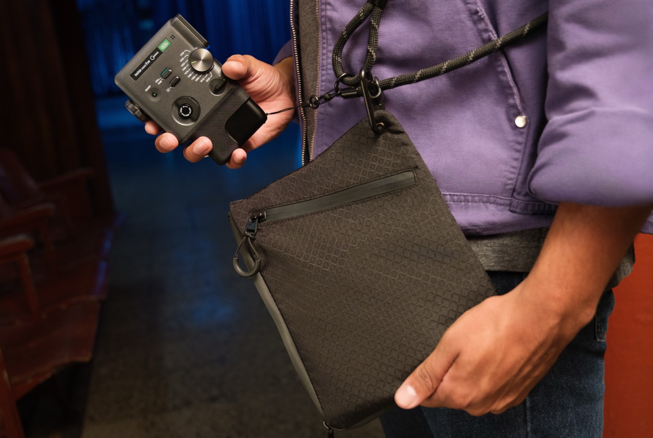 A person puts a Fujifilm camcorder in a black pouch around their body