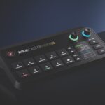 A black console from Rode with numerous buttons, placed on a shiny black surface with a dark blue background