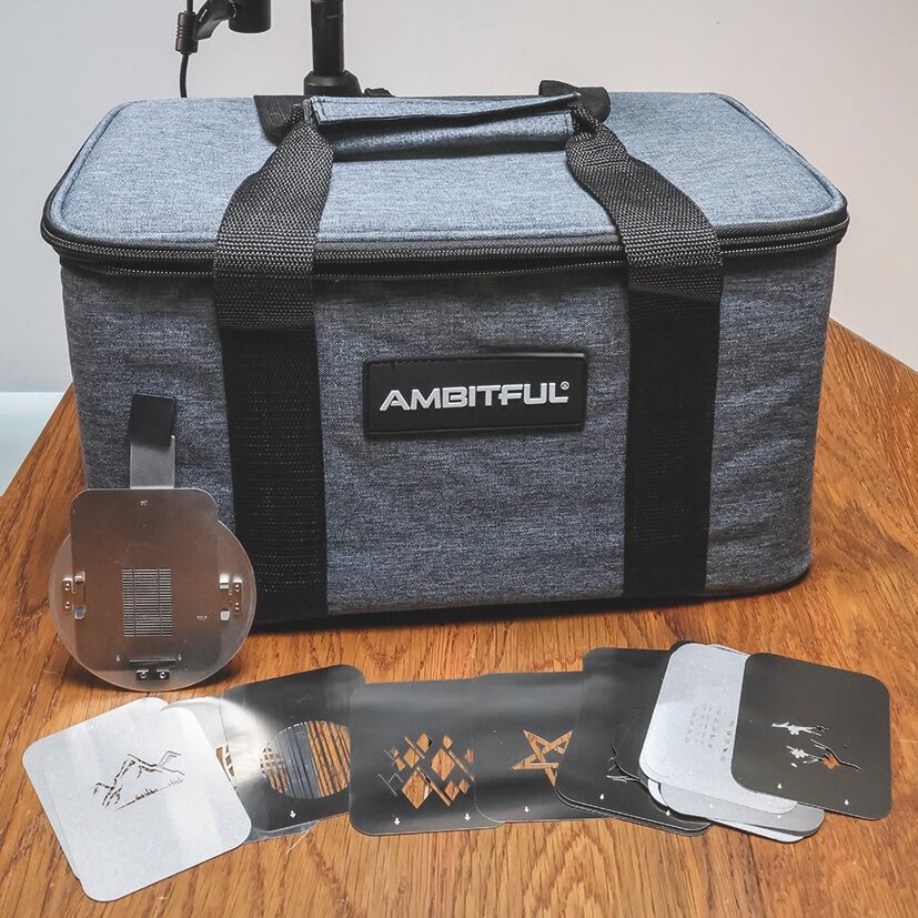 A projector, case and accessories from Ambitful spread on a wooden table
