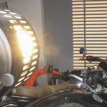 A large light shining on a motorbike placed inside a garage