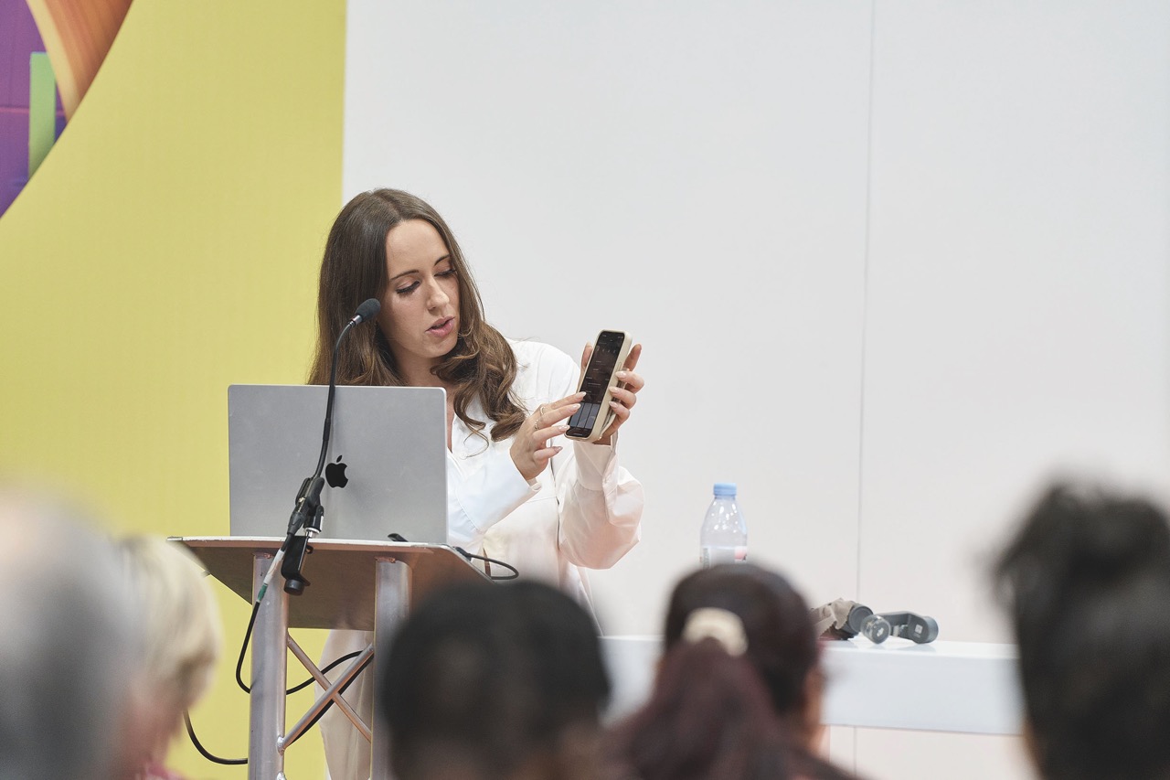 A woman presenting a phone as a speaker at an event