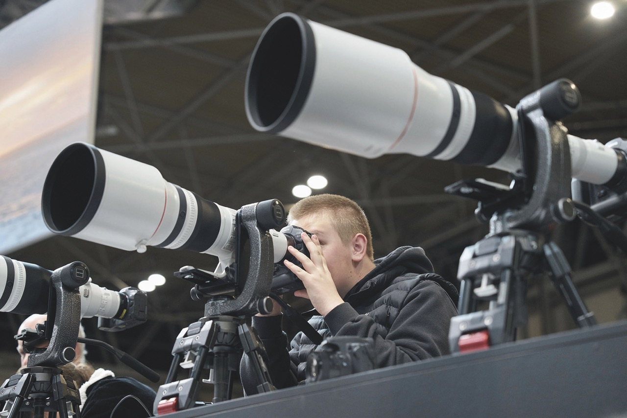 A person looking through a camera with a large lens, placed between other cameras