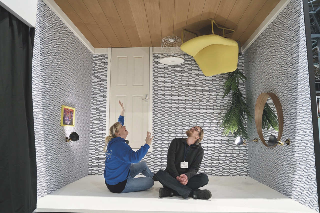 Two people sitting on the roof of an upside-down room
