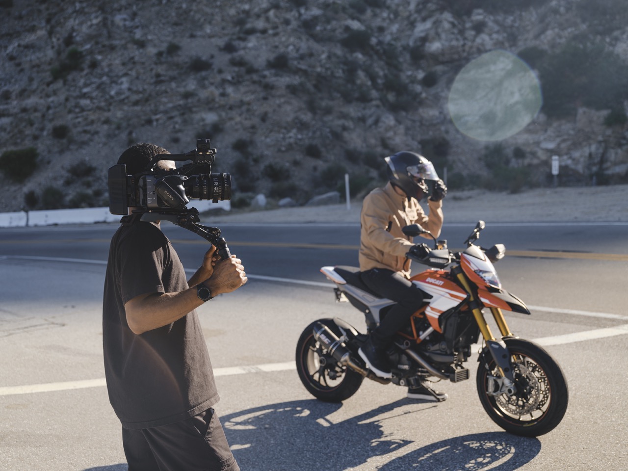 28-45mm AF Cine Zoom 030 Large A person holding a camera on their shoulder while another person rides a motorcycle