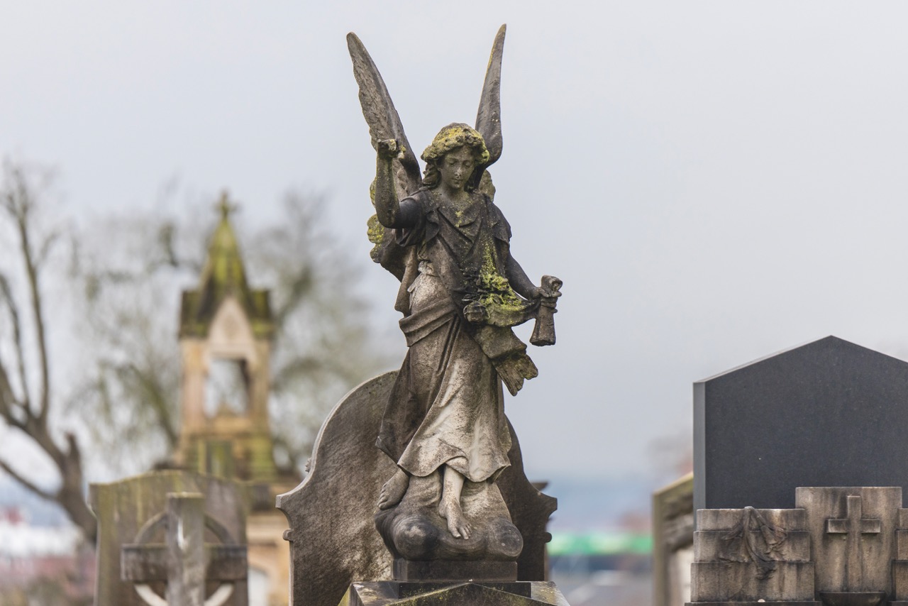 A stone statue of an angel in a graveyard