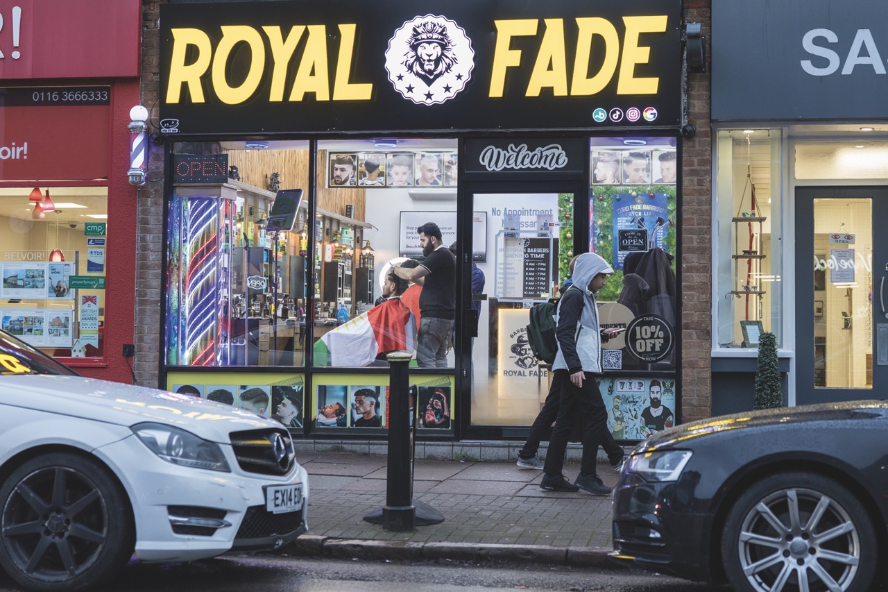 A barber storefront with cars parked outside
