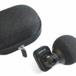 A small microphone from Shure next to a black case, against a white background