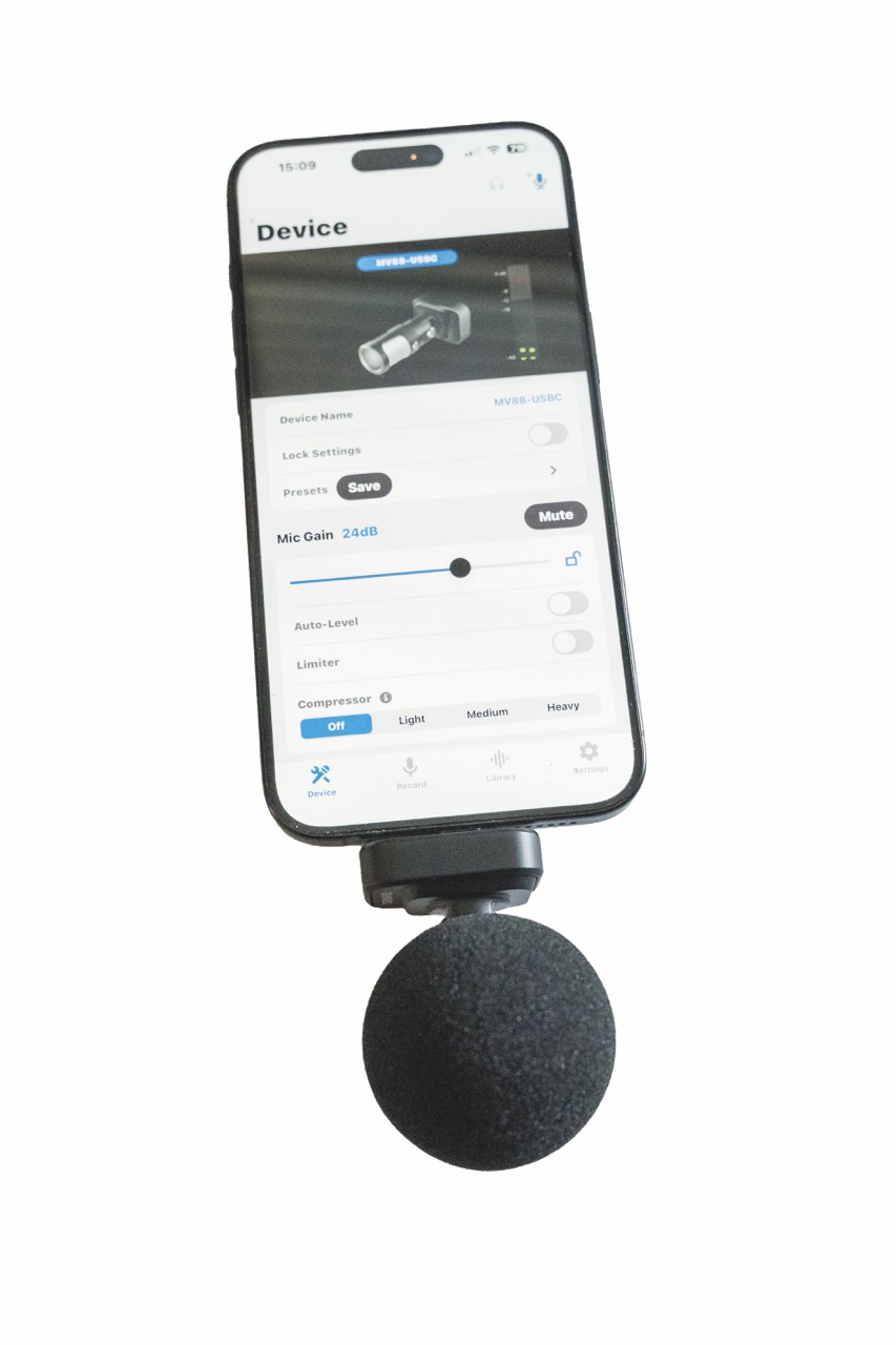 A phone with a round microphone from Shure attached to the bottom, against a white background
