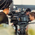 A group of people surrounding professional camera equipment at a conference