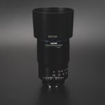 A Laowa lens standing vertically, against a dark background