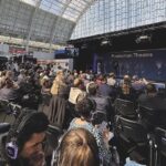 A busy conference hall with people wearing headphones and working together
