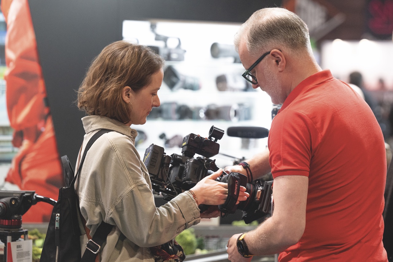 A man and woman discussing a camera at a conference
