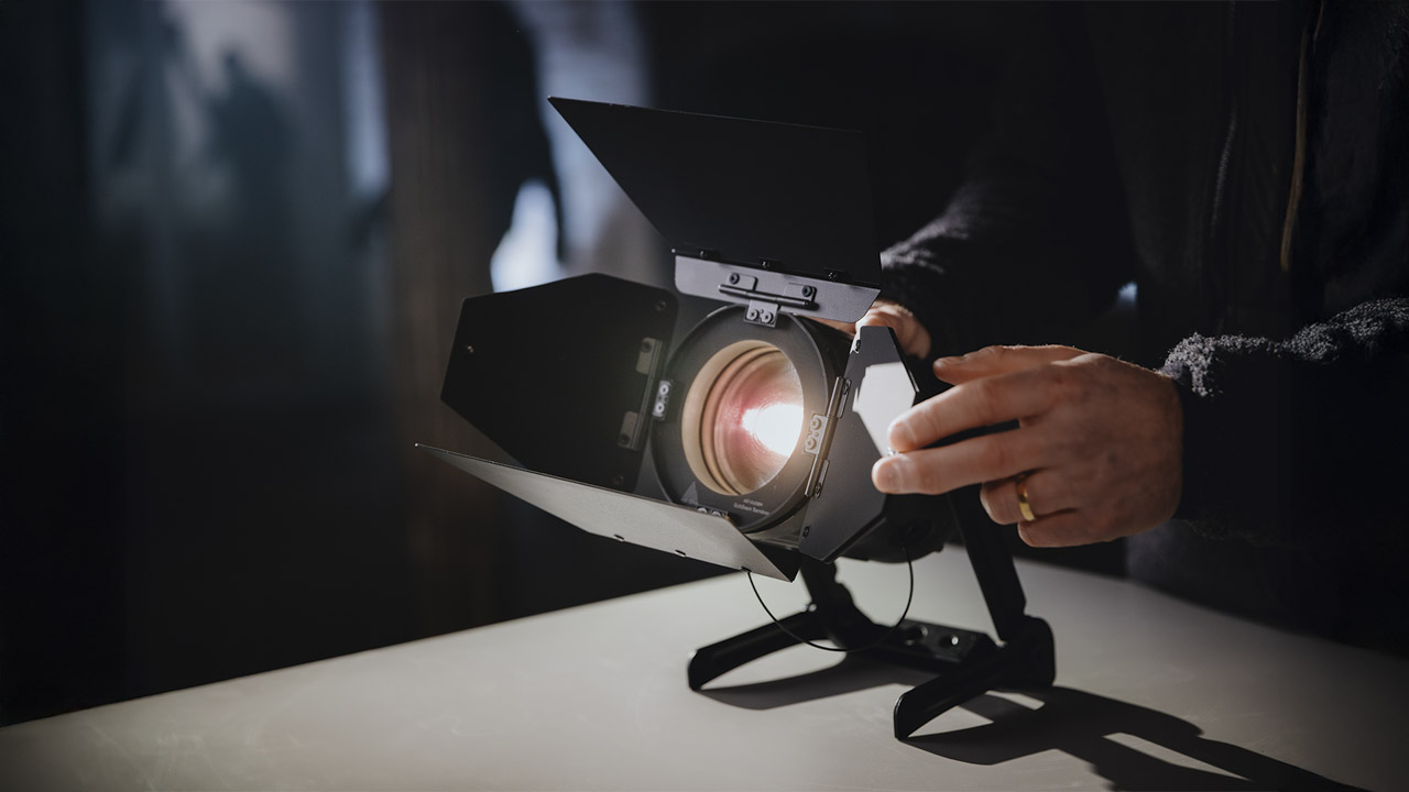 A hand adjusting the flaps on an Astera light, placed on a table