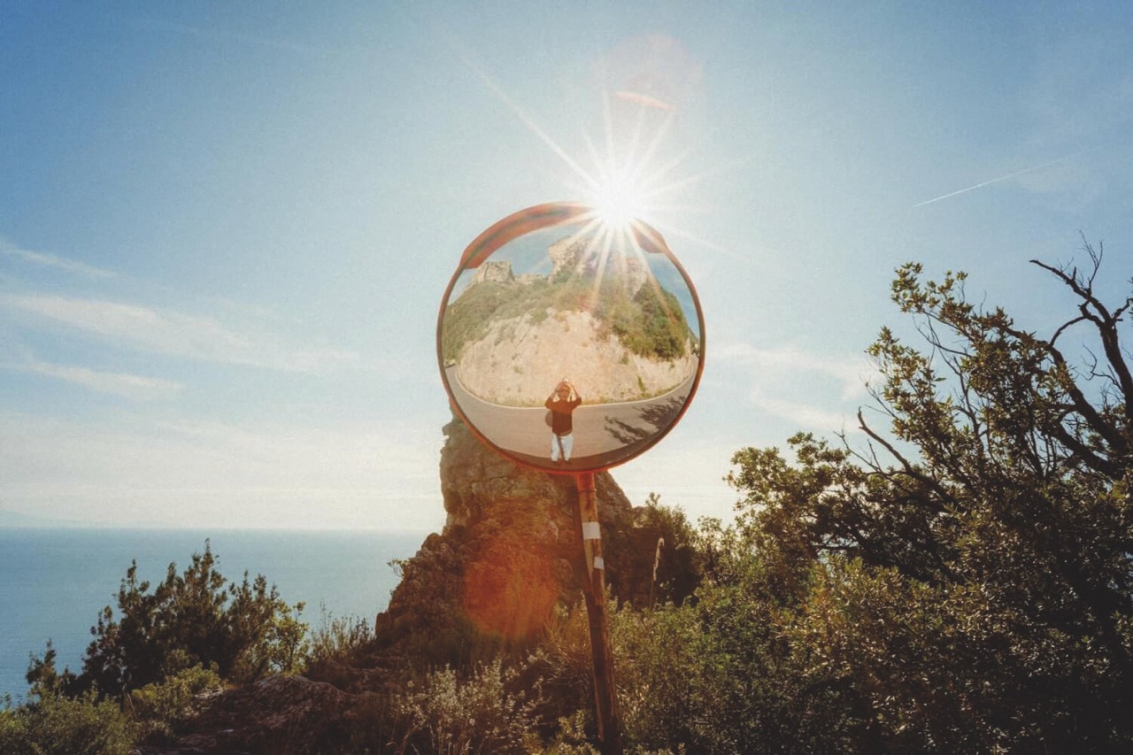 A person taking a photo in the reflection of a curved mirror